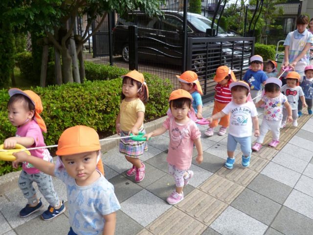 Bambini giapponesi in fila camminano lungo una strada - Watabi