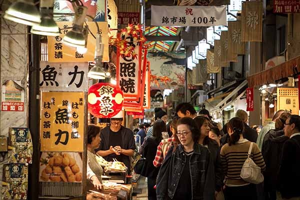 Il mercato Nishiki pieno di avventori che guardano la merce esposta